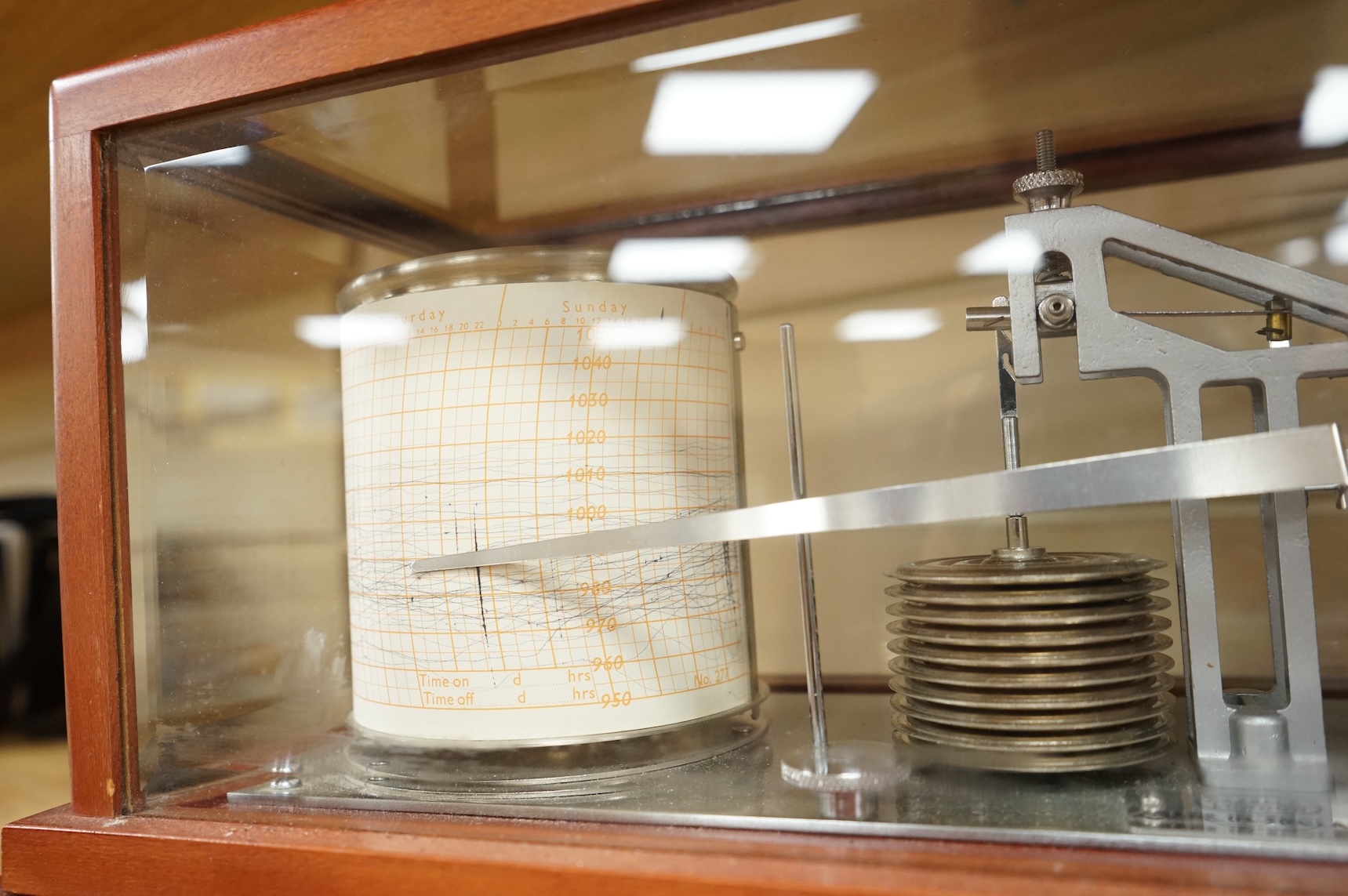 A 1970s Casella mahogany cased barograph with bevelled glass panels and a drawer underneath containing a good quantity of paper slips and instruction leaflet.